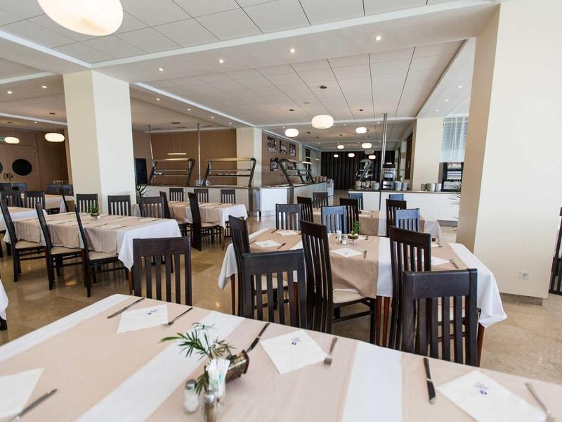 Spacious dining room with wooden tables and chairs, decorated tables, and bright lighting.