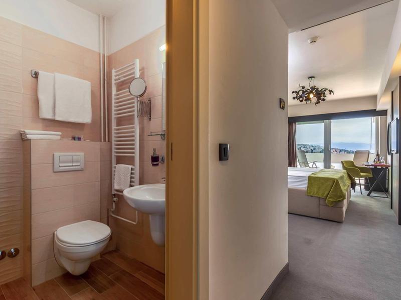 Bathroom and bedroom of a modern hotel room with a view of the landscape.