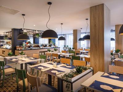 Modernes Restaurant mit Holzstühlen, großen schwarzen Lampen und grünen Pflanzen als Dekor.