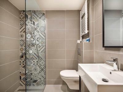 Modern bathroom with shower and decorative tiles in a hotel room.