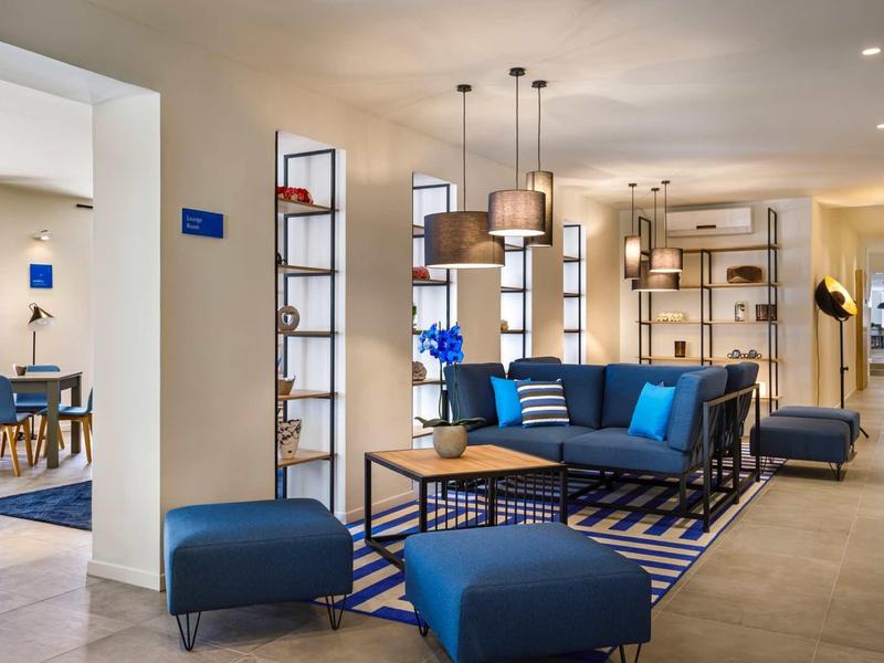 Bright hotel lounge area with blue upholstered furniture and modern lighting.