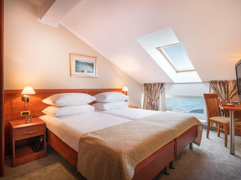 Gemütliches Schlafzimmer mit zwei Betten, Dachfenster, Holzmöbeln und warmem Licht.