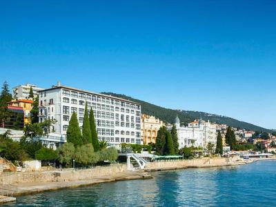 Hotel buildings along the coastline overlooking the sea and cliffs under a clear blue sky.