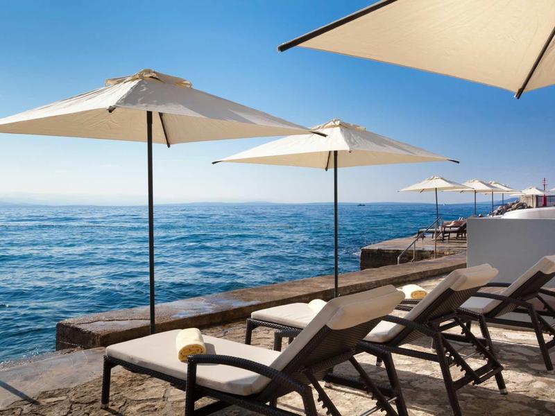 Sun loungers and umbrellas by the sea under a clear blue sky.