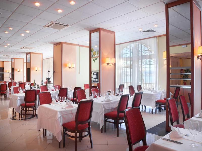 Elegant restaurant with set tables and red chairs in a bright room.