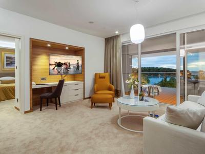 Habitación de hotel moderna con zona de estar, escritorio y balcón con vistas a las montañas.