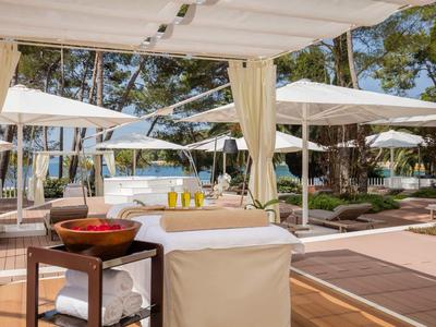 Zona de masajes al aire libre con tumbonas y sombrillas en un hotel.