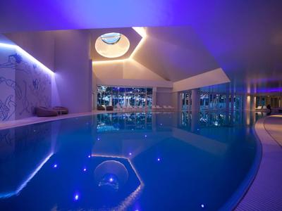 Piscina interior moderna con iluminación azul y ventanas panorámicas en un hotel.