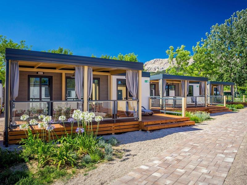 Case vacanza moderne con verande in legno in un ambiente verde e soleggiato.