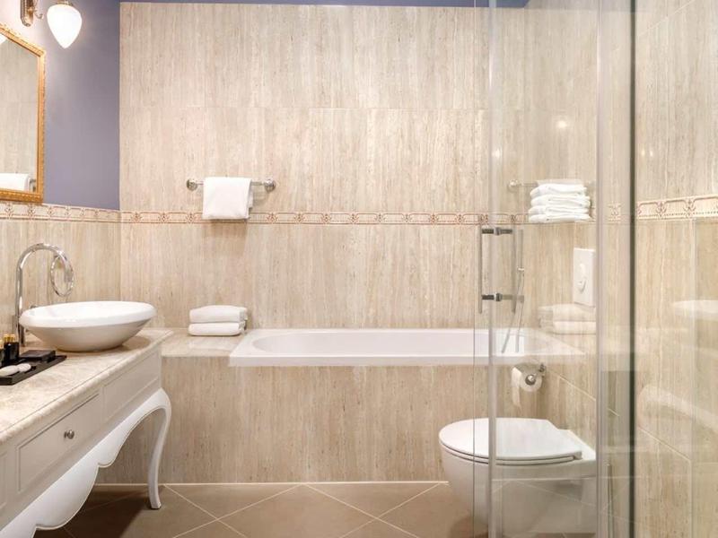 Modern bathroom with bathtub, sink, and glass shower in neutral tones.