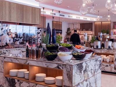 Nowoczesne bufet z marmurową wyspą, kieliszkami i miskami owoców w eleganckiej restauracji hotelowej.