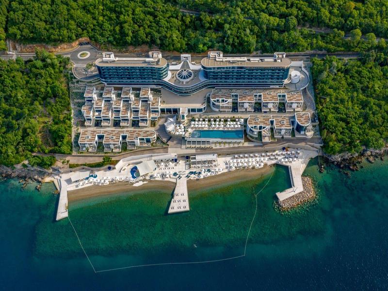 Aerial view of a seaside resort with pool and direct sea access.