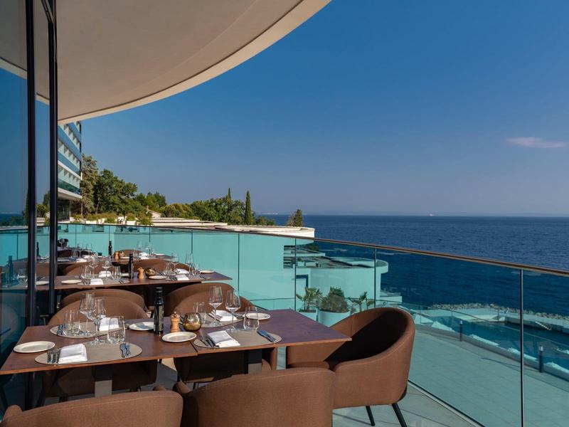 Terrace with tables and chairs by the sea under clear sky