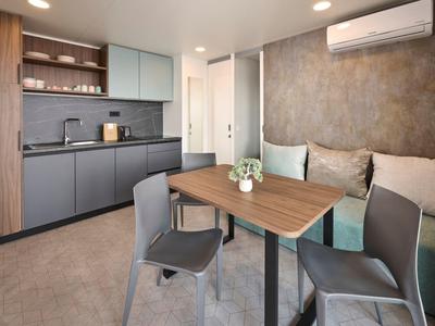 Moderner Küchen- und Essbereich mit grauen Schränken, Holzdetails und Sitzgelegenheiten.