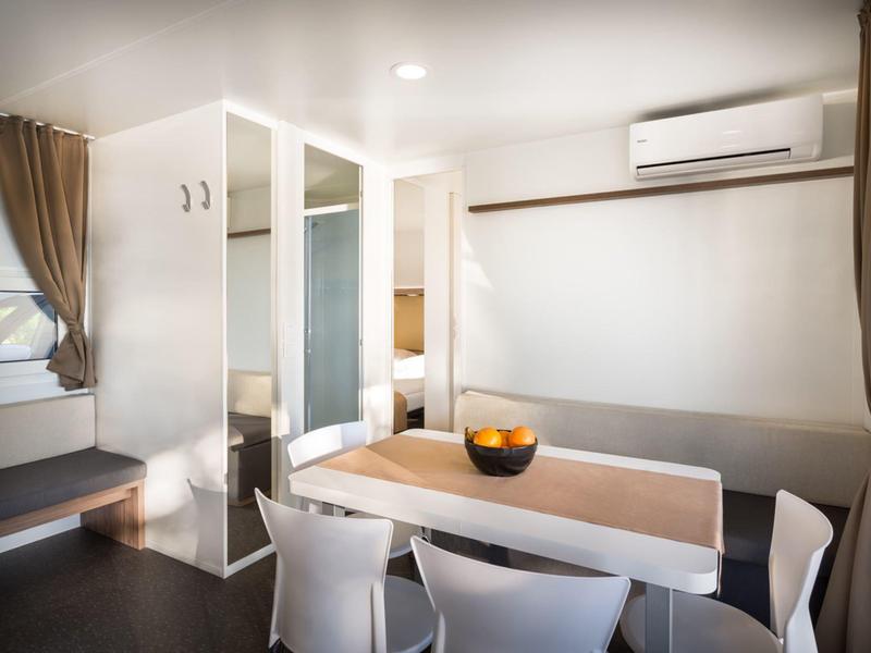 Modern eingerichteter Essbereich mit weißem Tisch, Stühlen und Klimaanlage an der Wand.