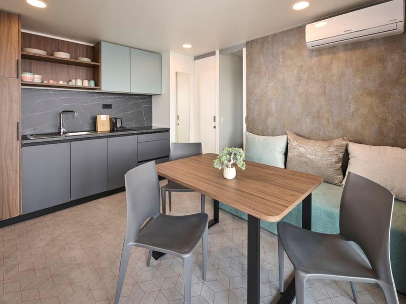 Moderner Küchen- und Essbereich mit grauen Schränken, Holzdetails und Sitzgelegenheiten.