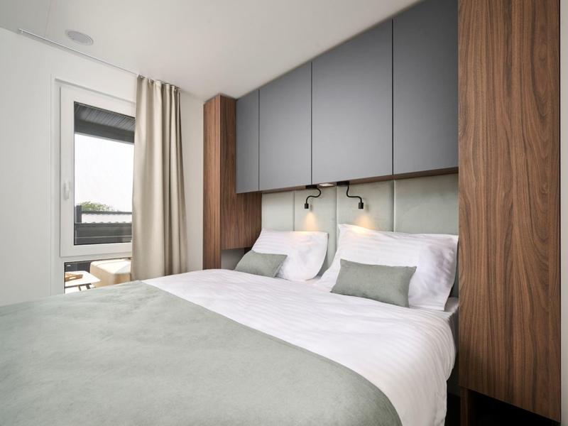 Modernes Schlafzimmer mit grauen Schränken und grün-weißem Bett.