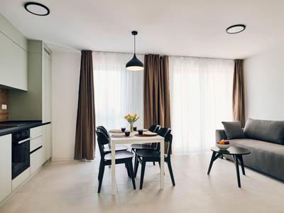 Modern living and dining area with sofa, dining table, and large windows.
