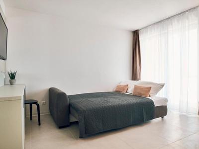 Modern hotel room with double bed, flat-screen TV, and floor-to-ceiling windows with curtains.