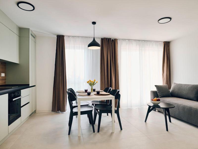 Modern living and dining area with sofa, dining table, and large windows.