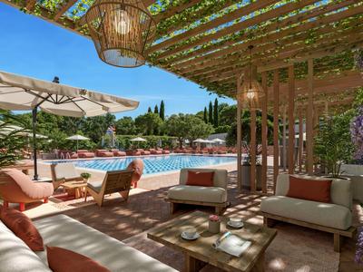 Gemütliche Poolterrasse mit Sofa, Holztisch, Sonnenschirm und Pergola in sonnigem Garten.