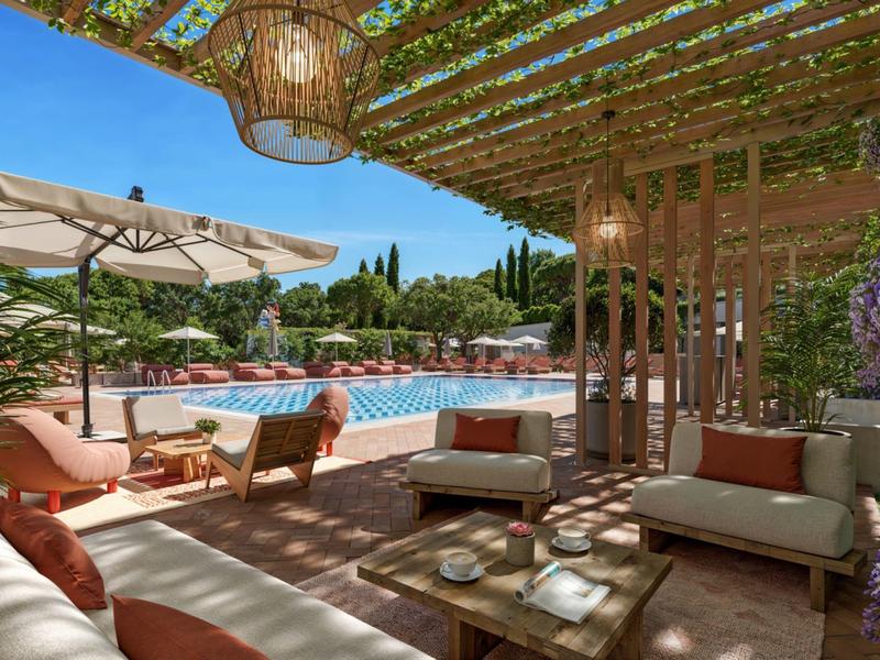 Pohodlná terasa s lounge nábytkem s výhledem na bazén pod modrou oblohou