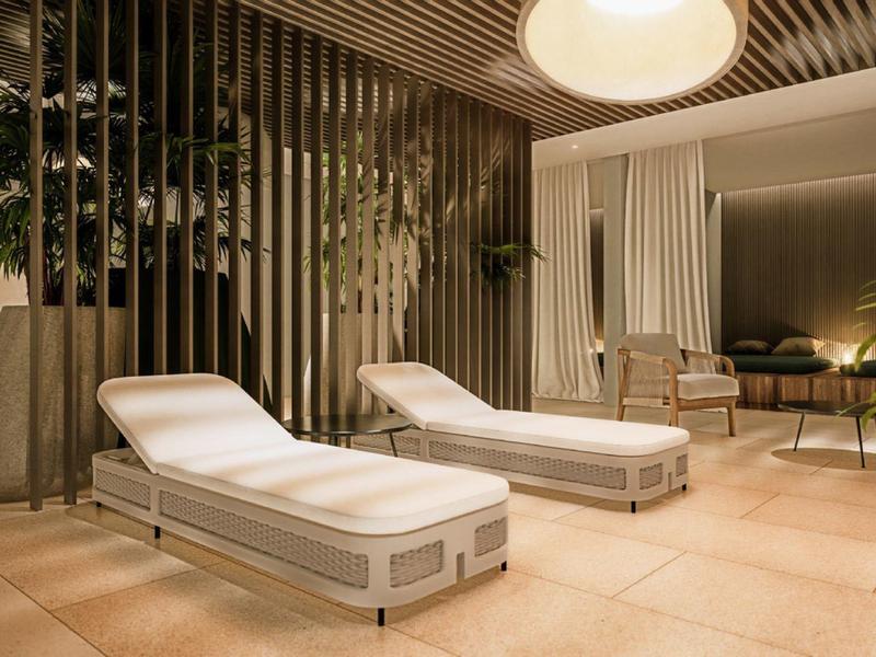 Moderní spa lounge s bílými lehátky, dřevěnými panely a nepřímým osvětlením.