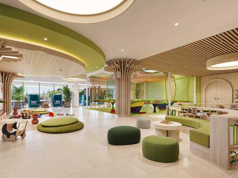 Prostorný moderní hotelový lounge s zeleným posezením a přirozeným světlem.