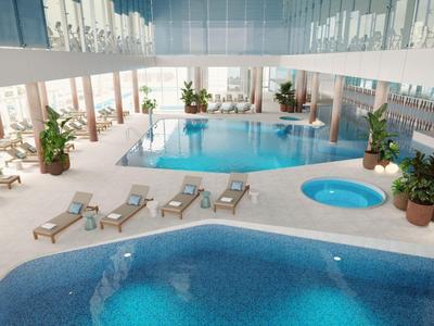 Ein moderner Innenpool mit Liegestühlen und Pflanzen in einem hellen Hotelbereich.