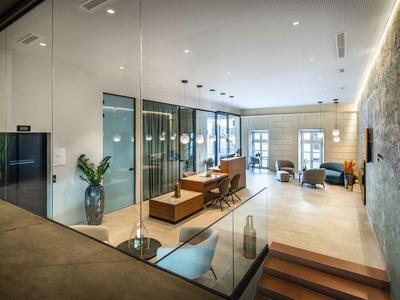 Moderner Hotel-Loungebereich mit Glaswänden, eleganten Möbeln und warmem Licht.