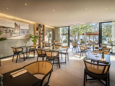 Hell eingerichteter Hotelrestaurantbereich mit Holztischen, Stühlen und großen Fenstern zur Terrasse.