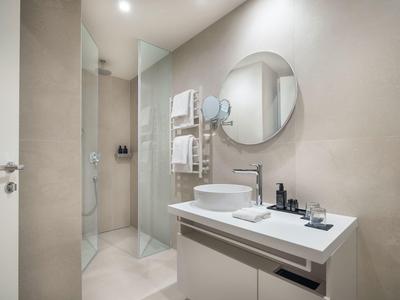 Modernes Badezimmer mit Waschbecken, Spiegel und begehbarer Dusche in neutralen Farben.