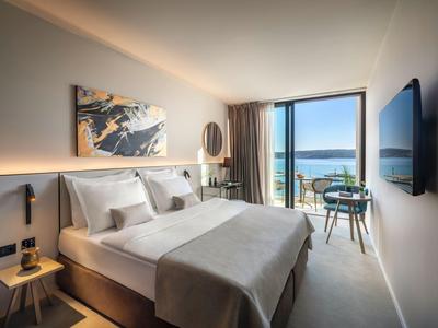 Modernes Hotelzimmer mit Doppelbett, Kunst an der Wand und Balkon mit Meerblick.