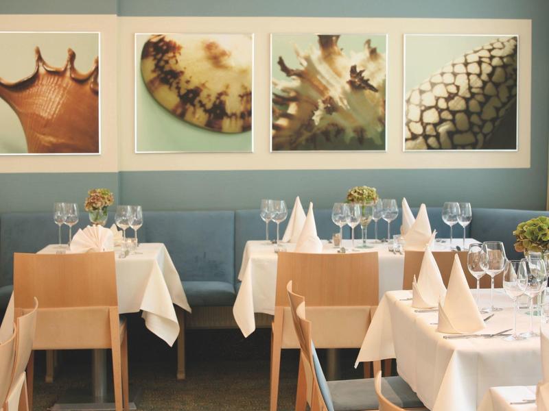 Elegantes Restaurant mit gedeckten Tischen, blauen Wänden und dekorativen Naturbildern.