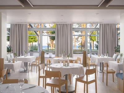 Bright, modern restaurant with wooden chairs and large windows overlooking a garden.