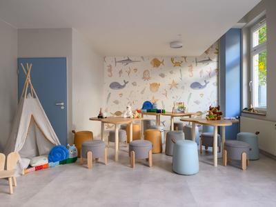 Child-friendly lounge with wooden furniture, tipi tent, and large windows.