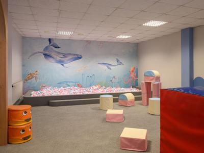 Children's play area with colorful cushions, dolphin mural, and soft gray carpet.
