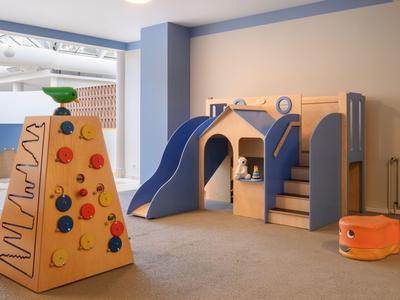 Children's play area with climbing wall, blue slide house, and orange seating cube.