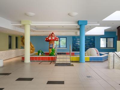 Indoor hotel area with children's playground, colorful pillars, and bright flooring.