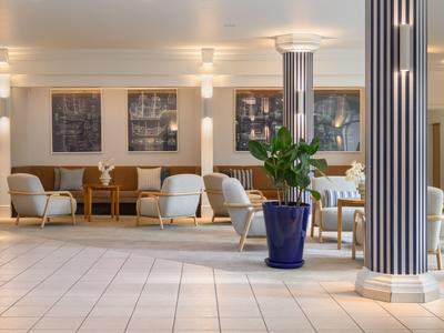 Bright hotel lobby area with striped columns, blue plant pots, and modern seating furniture.