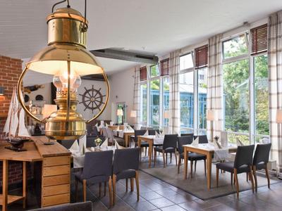 Modernes Hotelrestaurant mit großen Fenstern, Holzmöbeln und nautischen Dekorationen.