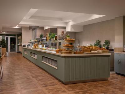 Moderní bufetová část s dřevěnou podlahou a různorodými jídly v hotelu.