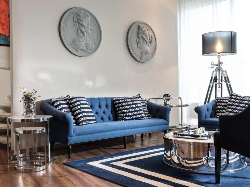 Modernes Wohnzimmer mit blauem Sofa, gestreiften Kissen, runden Wanddekorationen und Holzboden.