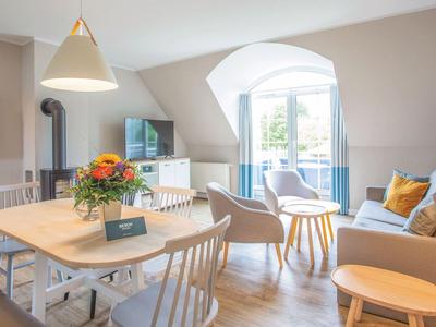 Helles Wohnzimmer mit Esstisch, gemütlicher Sofa-Ecke und offenem Fenster zu einer Terrasse.