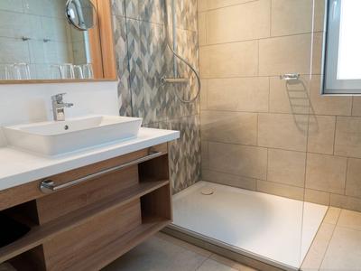 Modern bathroom with white sink, wooden cabinet, and shower area with curtain.
