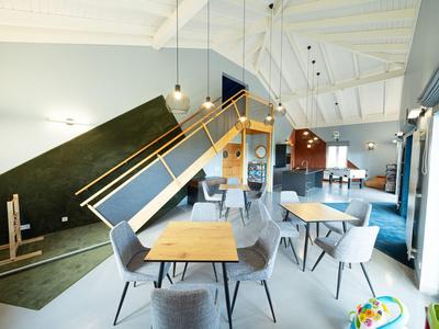 Modern hotel lounge area with tables, chairs, and a stylish staircase in the background.