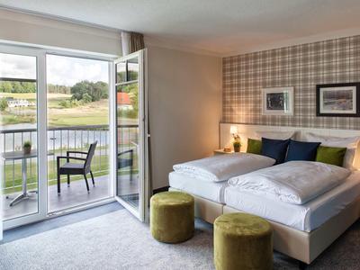 Helles Hotelzimmer mit Doppelbett, Balkon und ländlichem Ausblick.