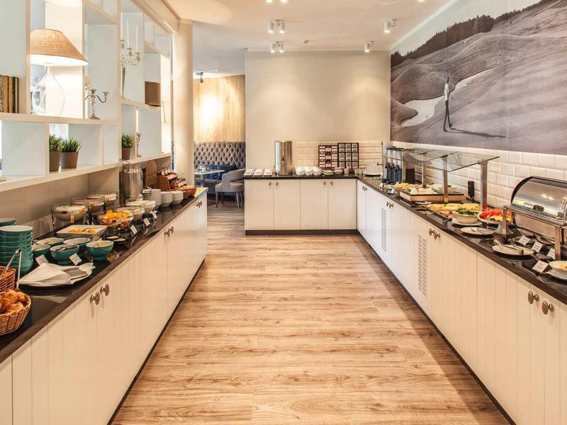 Modernes Buffet mit hellem Holzfußboden, weißen Schränken und verschiedenen Frühstücksoptionen.