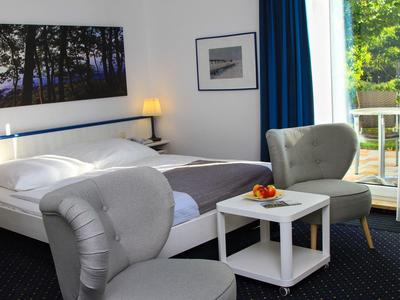 Modern eingerichtetes Hotelzimmer mit Doppelbett, Sitzbereich und Balkon mit Blick ins Grüne.