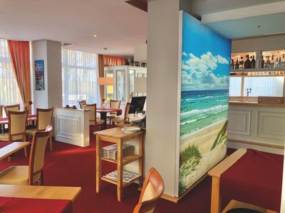 Gemütlicher Hotel-Loungebereich mit Sesseln, Tischen und einer Strandwanddekoration.